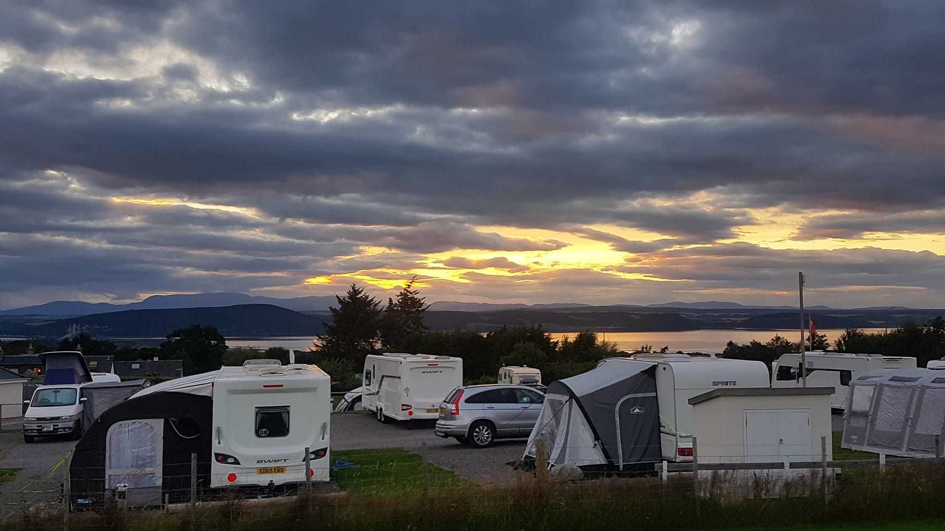 Residents of the RV community gather in a parking lot at sunset, contemplating the expansion of their group.