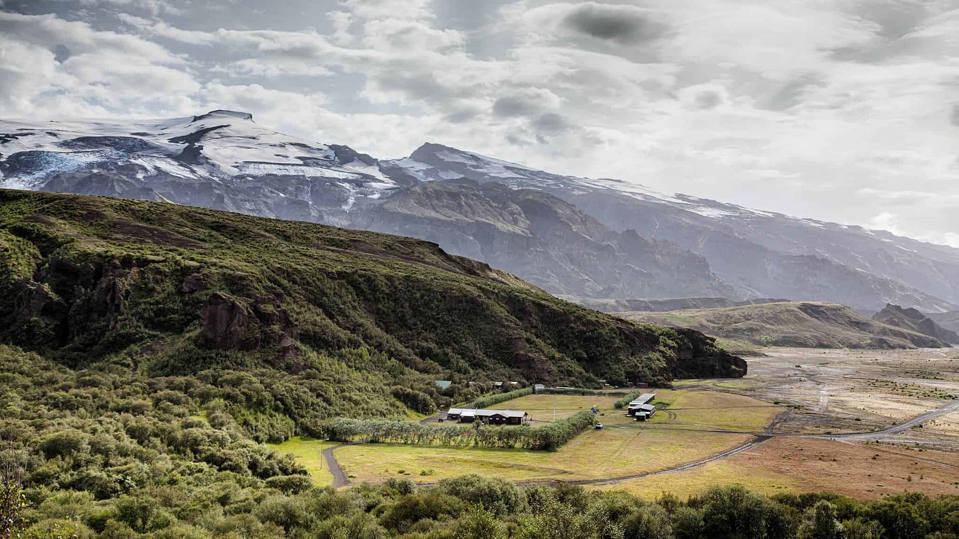 An aerial view of a valley with mountains in the background near Iceland's Volcano Huts.