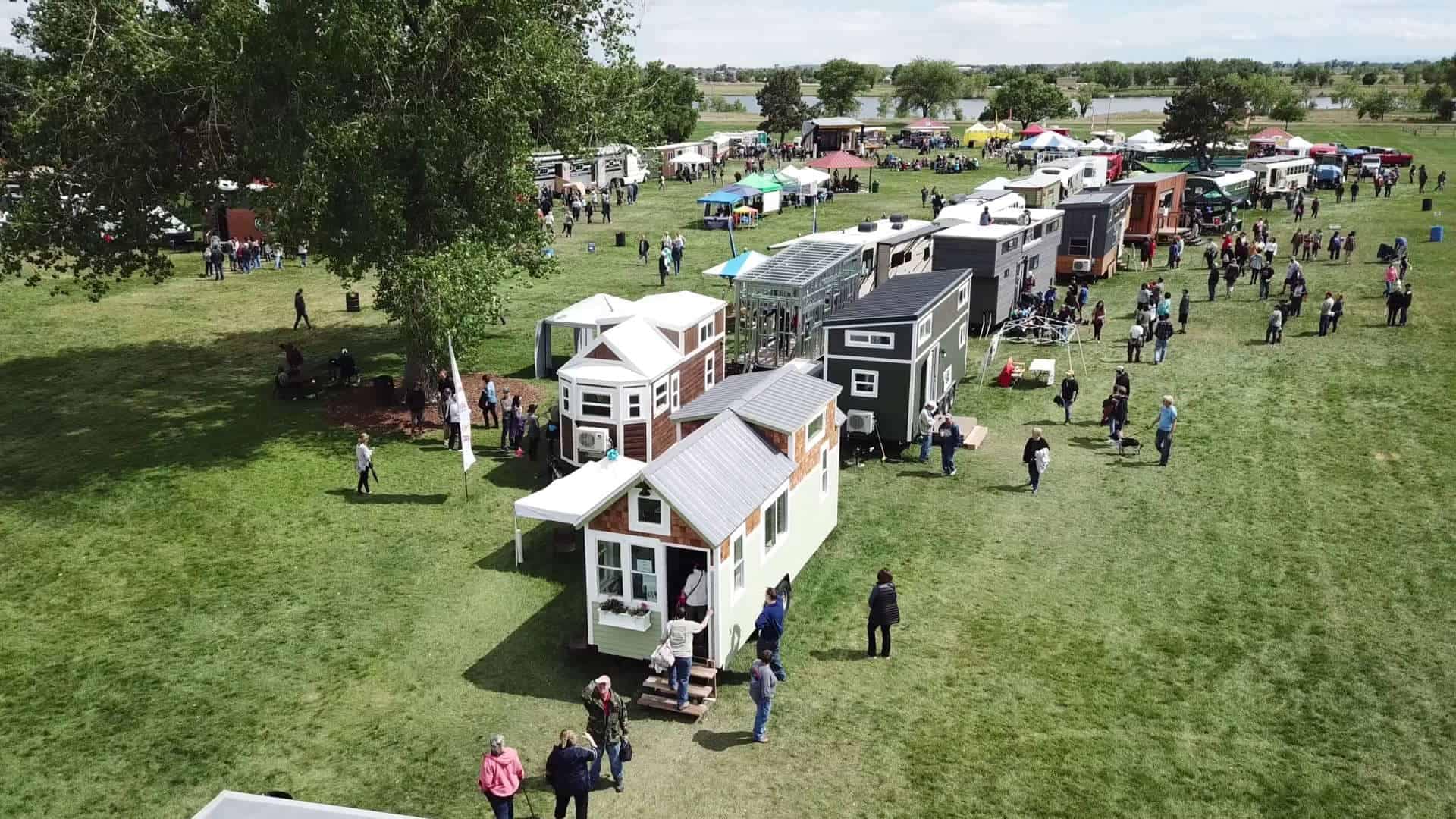 An aerial view of a crowd of people at the Colorado Tiny House Festival, featuring unique RVs and tiny homes.