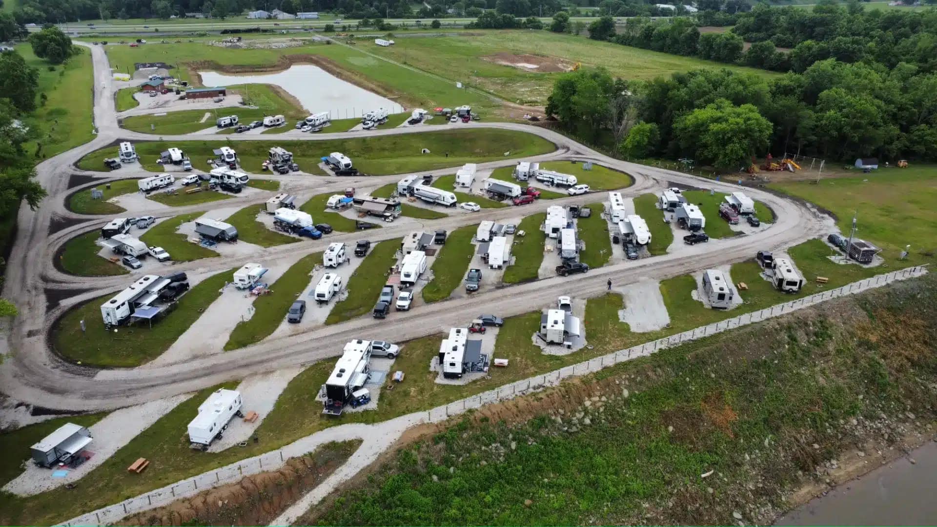 An aerial view of an RV park nestled along the Ohio River, providing a vibrant campground filled with many parked RVs for a memorable camping experience.