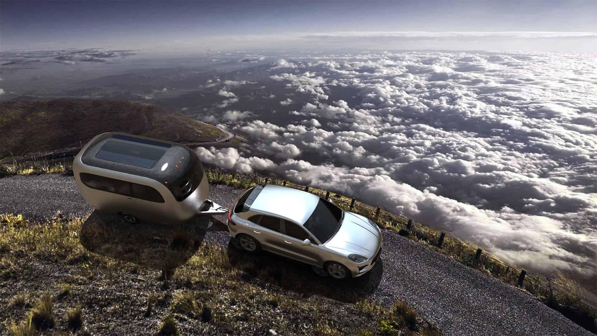 An urban-inspired travel trailer, designed by Studio F. A. Porsche, is cruising down a mountain road with clouds in the background.