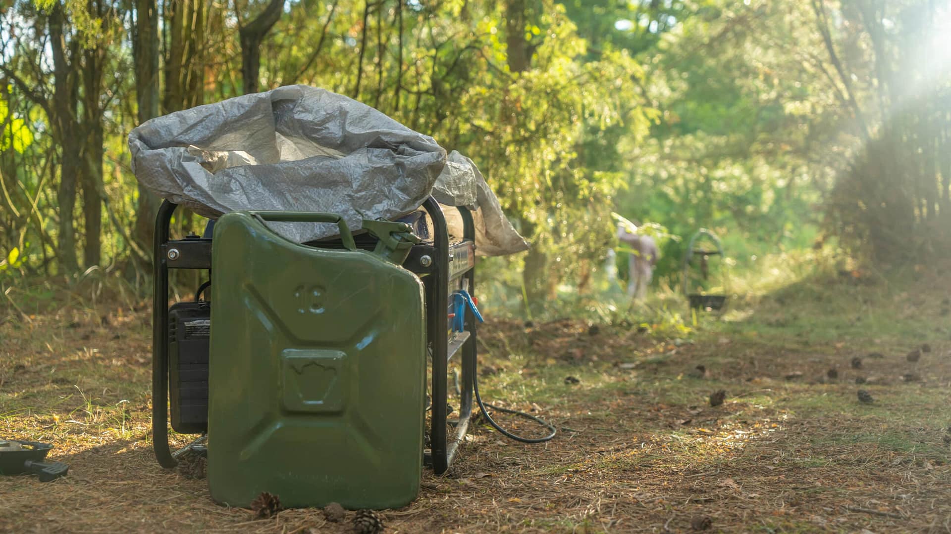 A gas can sitting on an auto-draft cart in a wooded area.