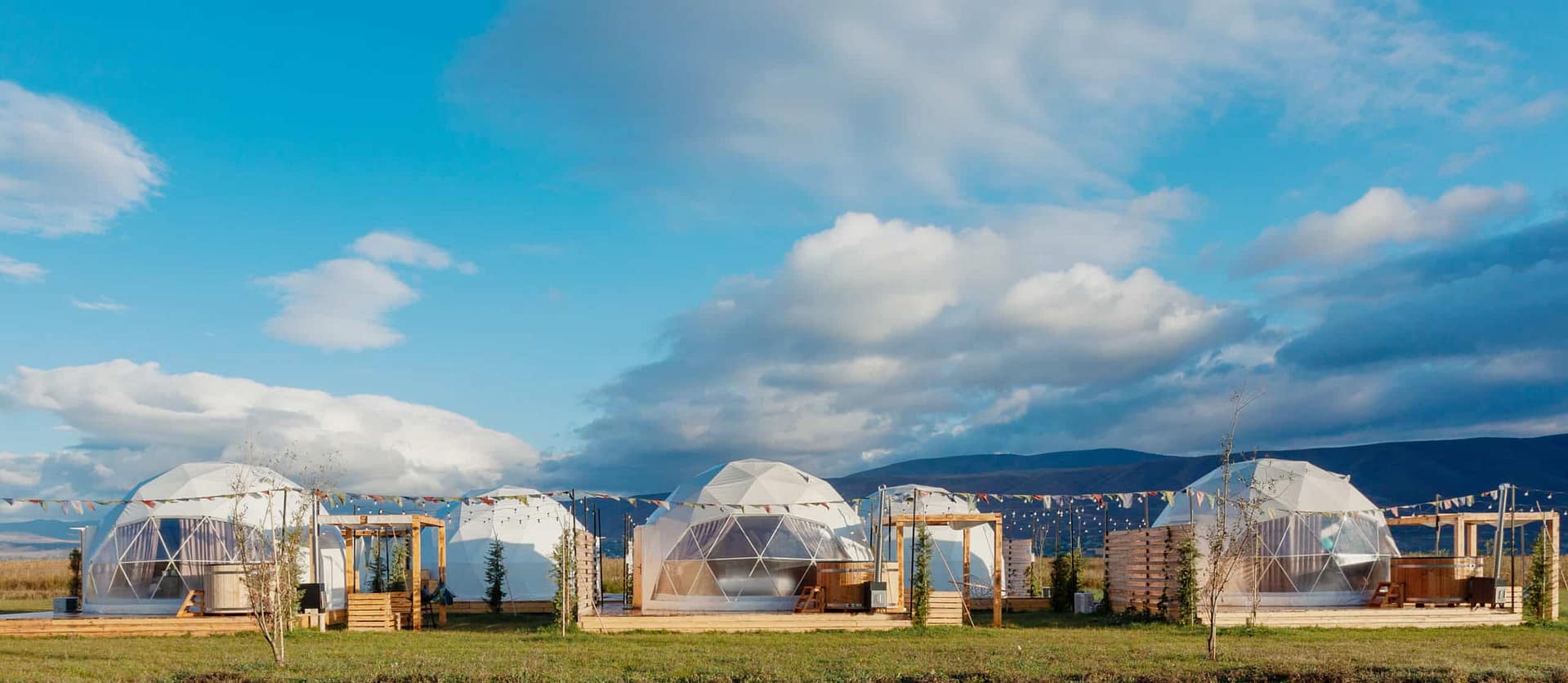 A global market of glamping tents set up in the middle of a grassy field.