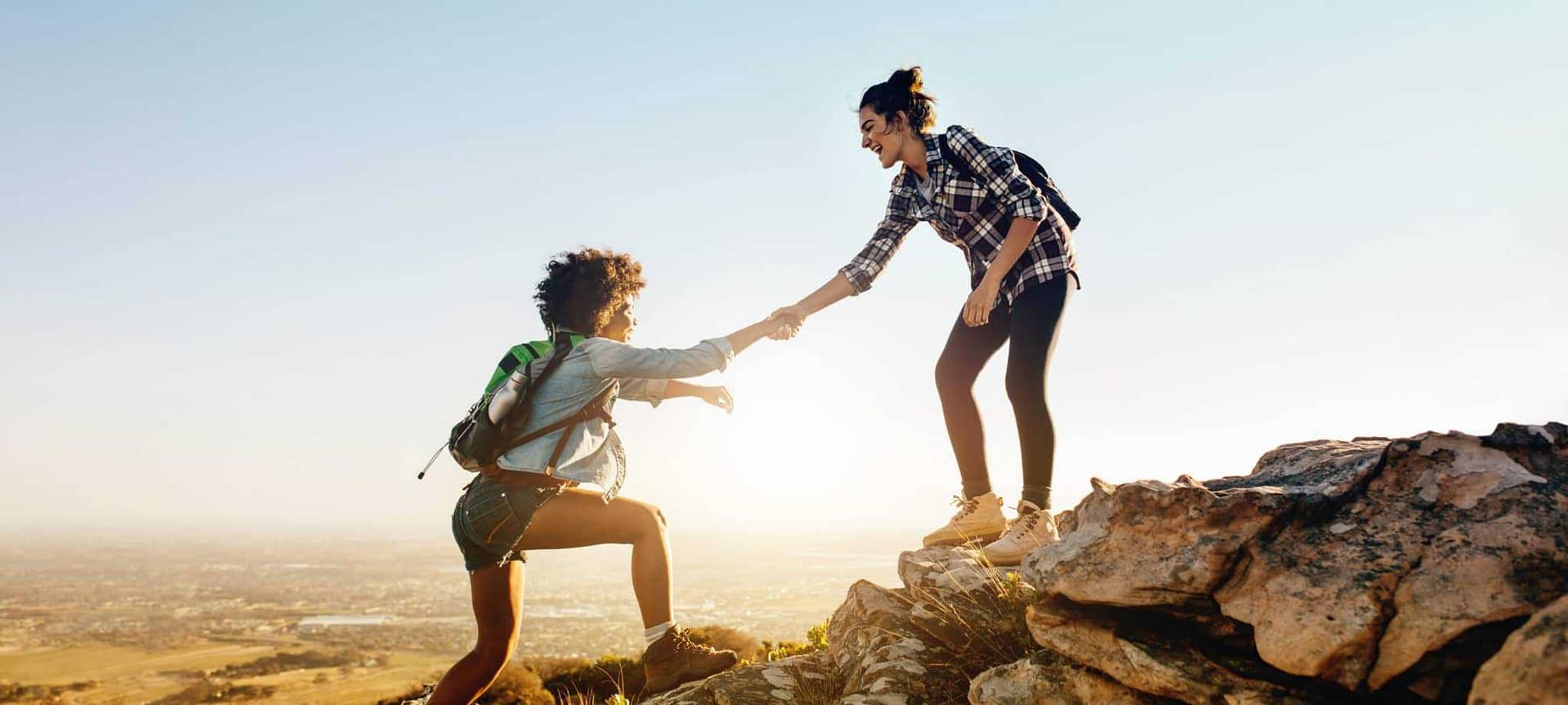Two women hiking together on top of a mountain.