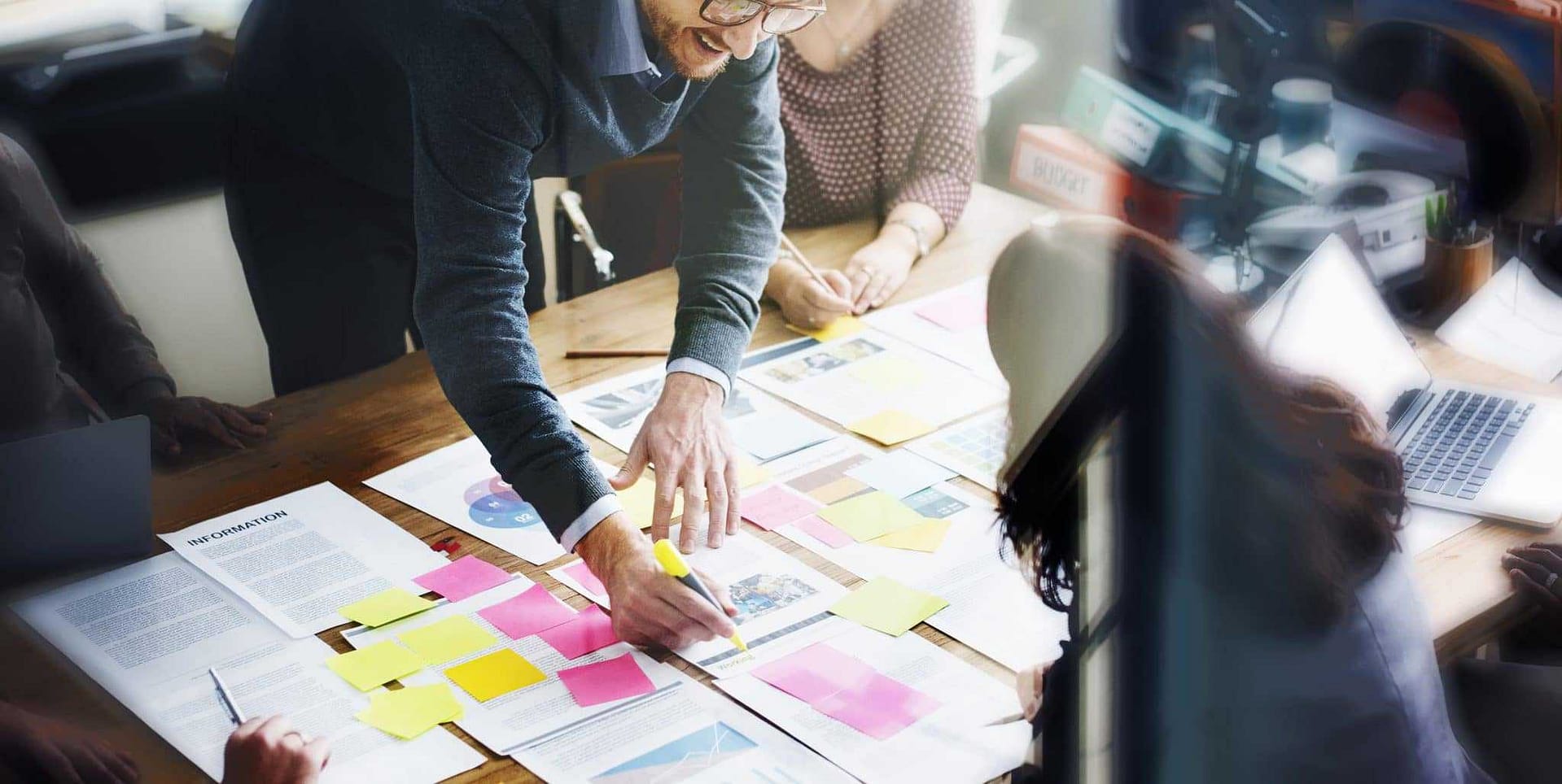 A group of people sitting around a table with sticky notes, collaborating on a Destination Management Plan for the Central Coast.