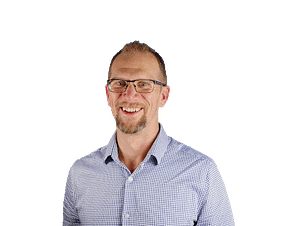 A smiling man wearing glasses and a blue shirt, engaged in software development.