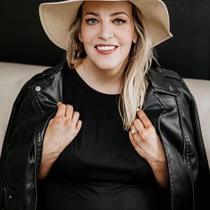 A pregnant woman wearing a hat and leather jacket while RVing.