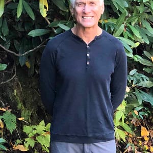 A man in a black shirt standing in the wooded Big Rig Friendly RV Resort.
