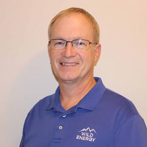 A man wearing a blue polo shirt is standing in front of a wall.