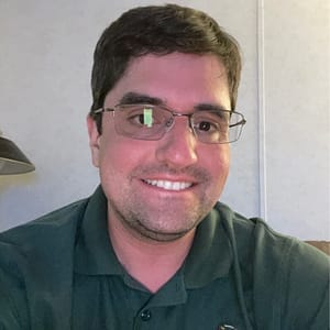 A man wearing glasses and a green shirt at the MC Fireside Chats event on December 21st, 2022.