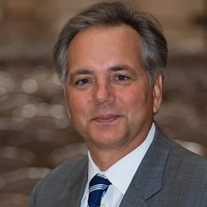 A man in a suit and tie is posing for a photo during the MC Fireside Chats on December 21st.