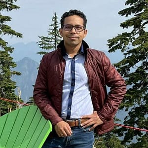 A man standing in front of a green chair with mountains in the background during the MC Fireside Chats event on July 26th, 2023.