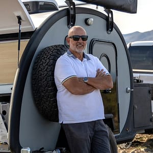 A man standing in front of a camper trailer hosting MC Fireside Chats on September 27th.