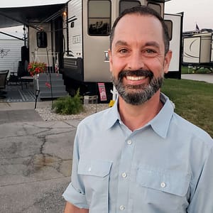 A man smiling in front of an RV during Fireside Chats.