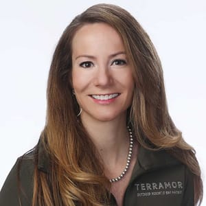 A woman in a green jacket is smiling at the MC Fireside Chats on February 21st, 2024.