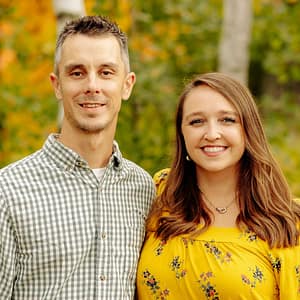 A man and woman posing in front of trees at the MC Fireside Chats on January 31st, 2024.