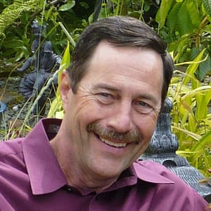 A man with a moustache smiling in front of a statue during the MC Fireside Chats on February 21st, 2024.