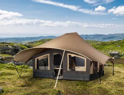 A stylish European tent stands proudly atop a hill, with majestic mountains looming in the background.