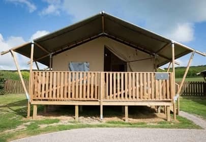 Sandford Holiday Park offers glamping pitches with tents featuring a wooden deck and railings.