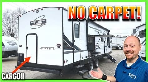 A man is standing in front of a Coachmen Northern Spirit RV.