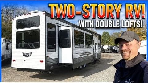 A man is standing in front of a Travel Trailer with Double Lofts.