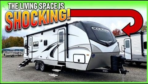 A 2022 Cougar RV with a black and white exterior, featuring a sign that boldly proclaims the living space to be shocking.
