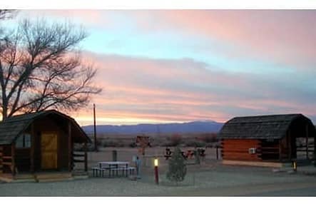 Two small cabins at Pueblo KOA Journey in the desert at sunset.