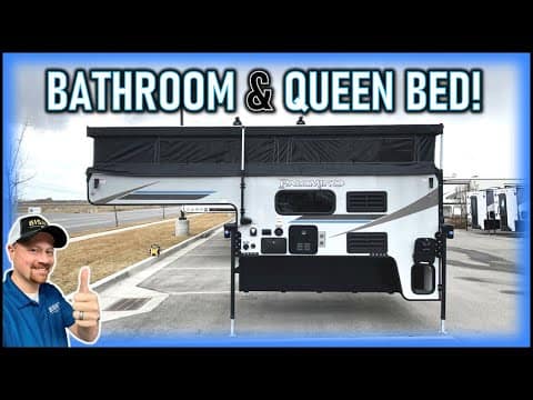 A man is giving a thumbs up to an Off-Grid RV with a queen bed + full bath.