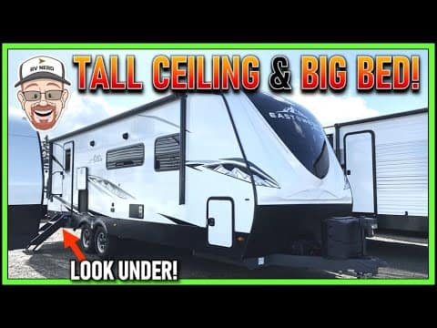 A picture of an RV with a bigger bed and a taller ceiling.