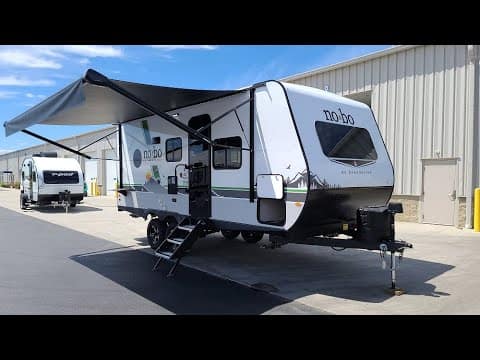 A white Forest River travel trailer parked in front of a building.