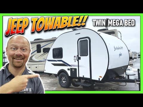 A man is pointing to a Explore Towable Twin Mega Bed in the Great Outdoors.