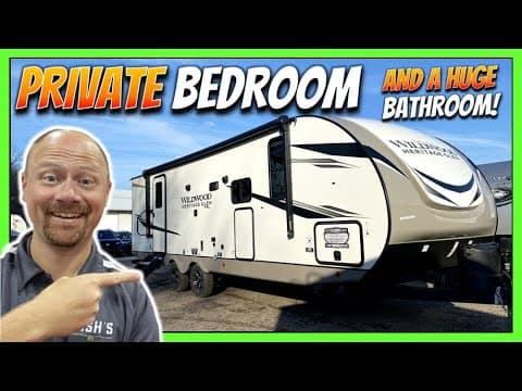 A man is pointing to his Wildwood Heritage Glen Hyper-Lyte RV with the words private bedroom and bathroom.
