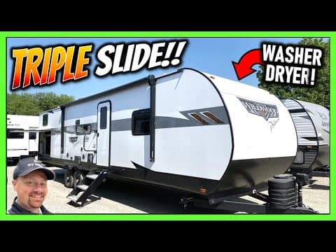 A picture of a 2023 Wildwood 33TS Travel Trailer, an rv with a sign that says triple slide, perfect for exploring.