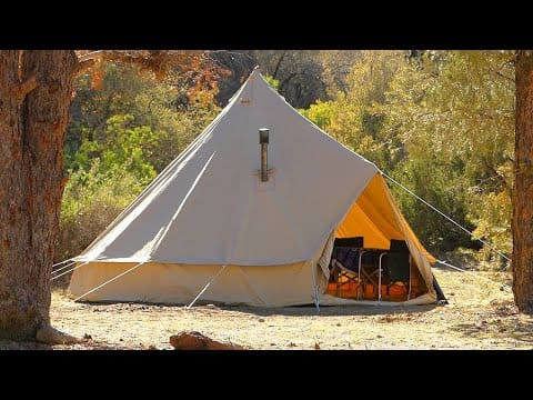 An exploration-themed canvas bell tent set up in the woods, offering a unique glamping experience.