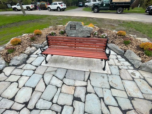 Former Campground Manager honors Webster Park with a bench in the middle of a stone walkway.
