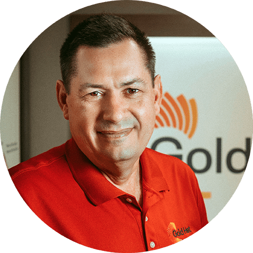 A man named Brian Bishop, wearing a red shirt, stands in front of a gold sign in the RV Industry Success.