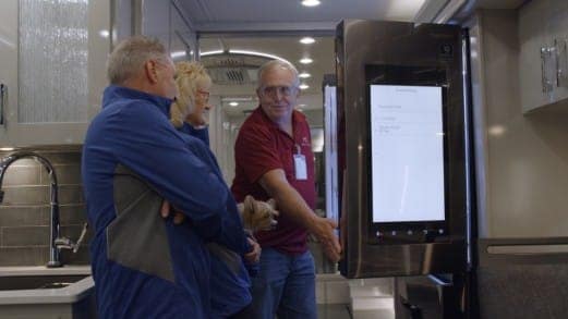 A group of people having an Experience looking at a refrigerator in a kitchen.
