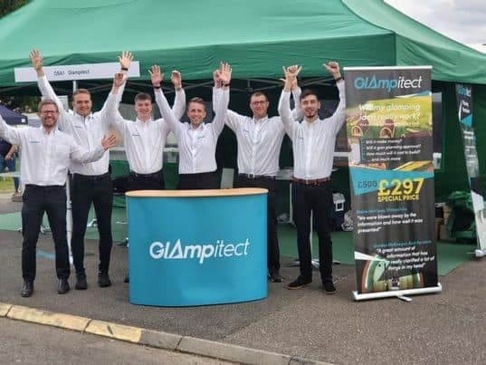 A group of people standing in front of a glamping tent.