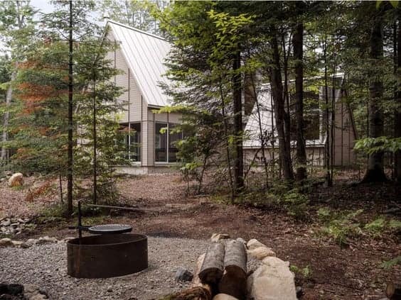A Quebec cabin nestled in the woods, available for rent with a fire pit, promoting land conservation.