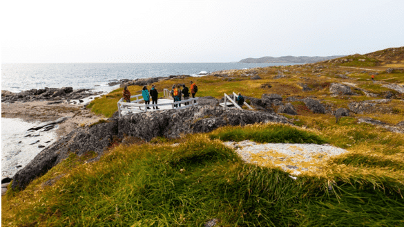 Visitors at a Labrador cliffside, part of the Parks Canada Sites in Newfoundland, gazing at the vast ocean.