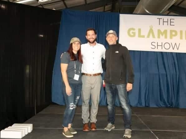 Three people from Timberline Glamping Co standing in front of a sign that says the Glampie Show, celebrating their industry award for innovation.