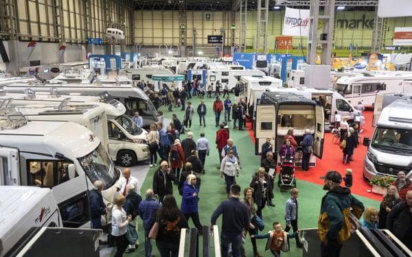 A group of people exploring UK Caravans and Motorhomes in a large hall at the Motorhome Show.