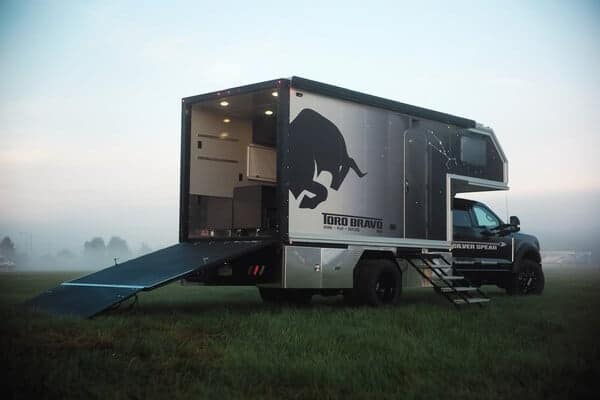 A TORO BRAVO truck with a Silver Spear camper attached to it in the middle of a field.