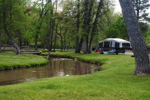 A camper enjoys the peaceful atmosphere next to a stream in the Spearfish Campground.