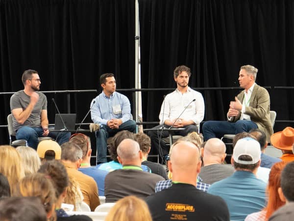 A group of men sitting on a stage in front of an audience at the Investment Pitch Event.