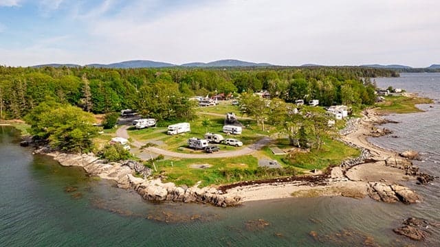 An aerial view of the Oceanside KOA Holiday RV park on an island, showcasing its expansion in the scenic Bar Harbor area.