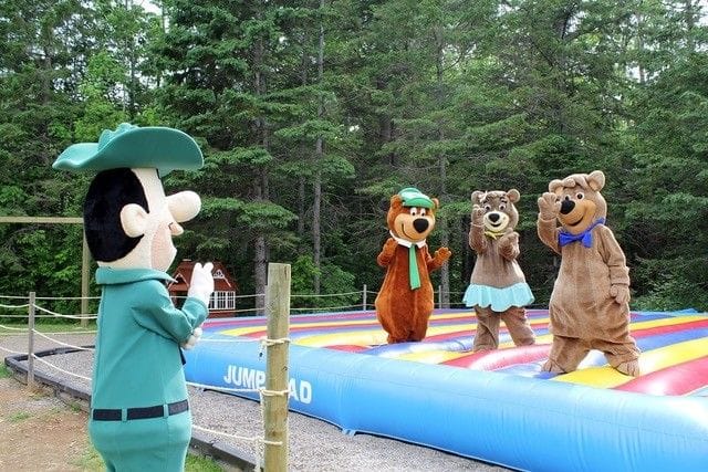 A group of mascots at Jellystone Park, Canada, bouncing on an inflatable trampoline.