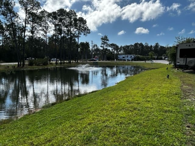 Sugar Sands RV Resort offers a serene and nature-filled experience with its picturesque pond, creating an inviting atmosphere for campers to relax and enjoy the beautiful wetlands.