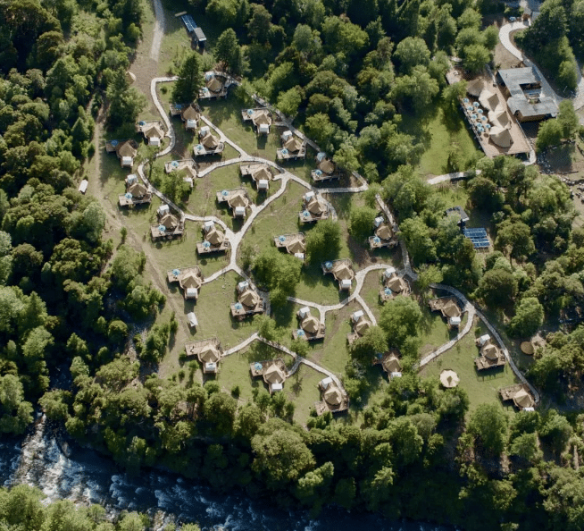 An aerial view of the Songtsam lodge nestled amidst towering trees, creating a tranquil glamping site in Tibet.