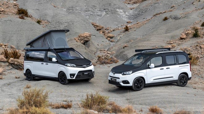 Two Toyota camper vans parked in a rocky area at the Spain Caravaning Expo.
